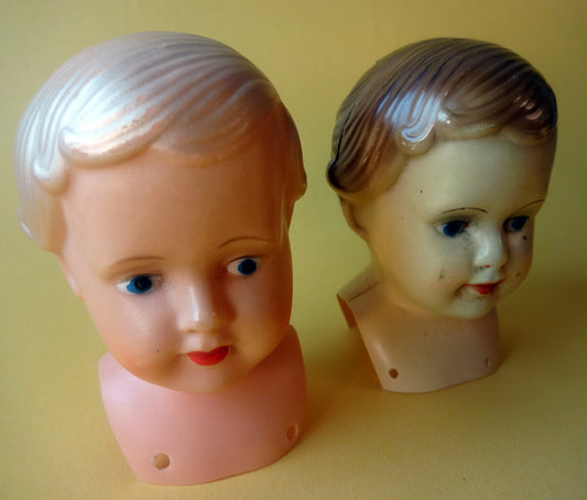 To dukkehoveder af celluloid og plastik, stemplet på ryggen.