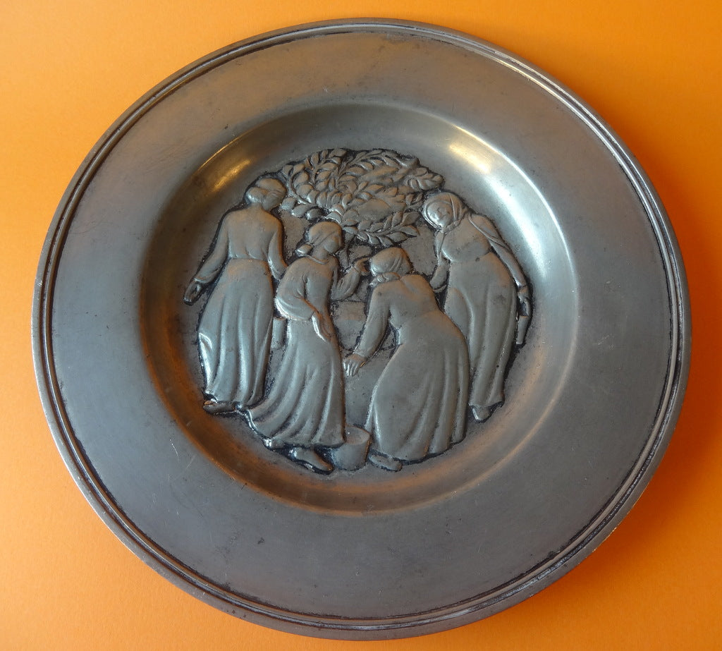 Lille fad af tin med relief af fire kvinder ved brønd, stemplet Just Andersen Danmark, nr. 2412.