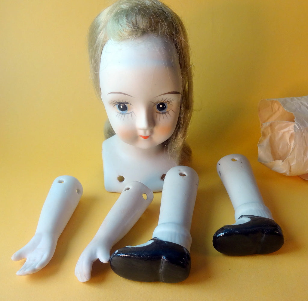 Dukkehoved med løs paryk, arme og ben i porcelæn.
