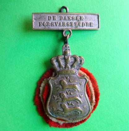 Emblem for De Danske Forsvarsbrødre i forsølvet messing. 
