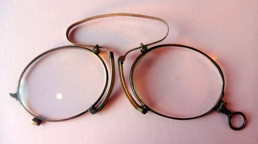 Et par gamle briller i forgyldt metal, med næseklemme.