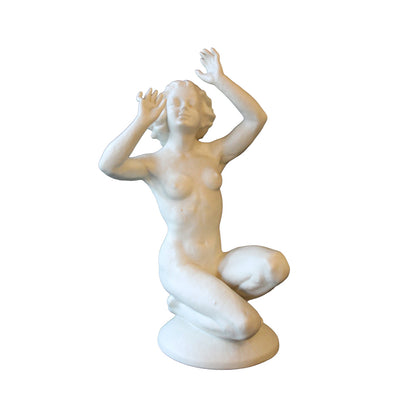Figur af porcelæn forestillende nøgen kvinde siddende